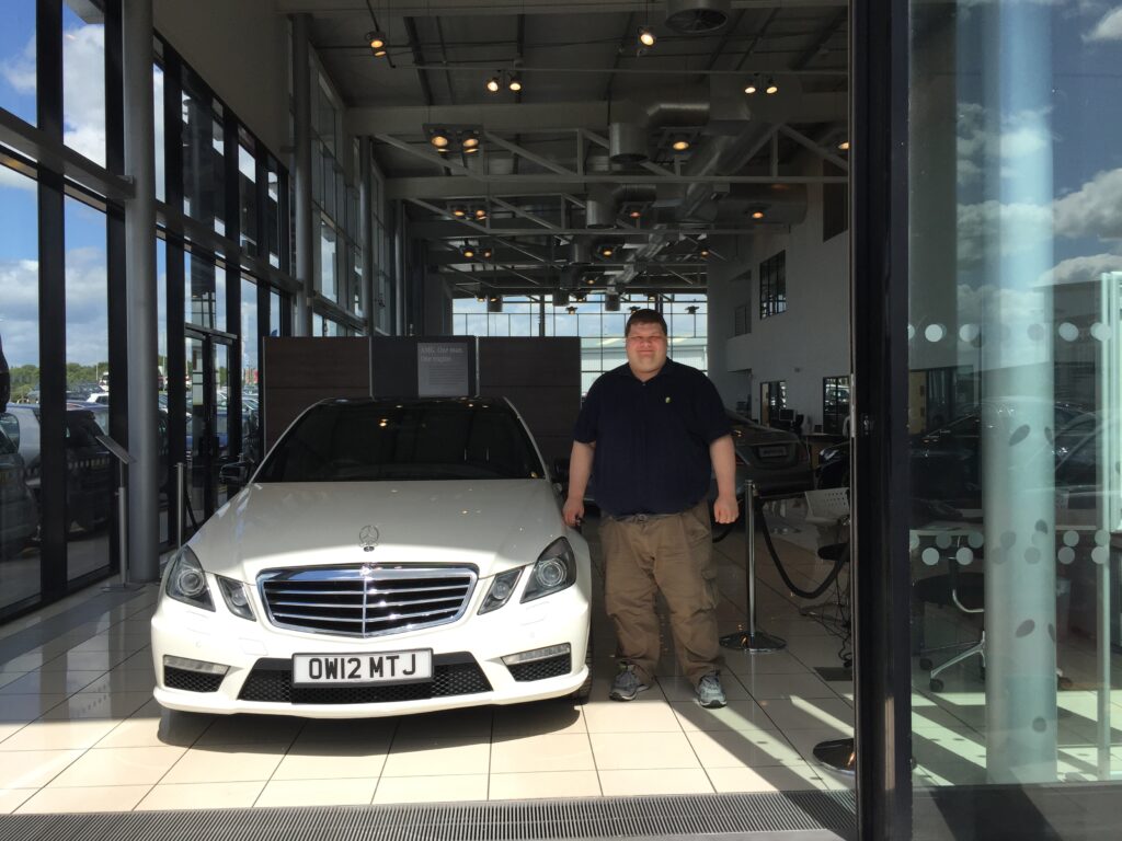 A photo of Tim Dixon picking his white Mercedes AMG E63 car up from the showroom in June 2015