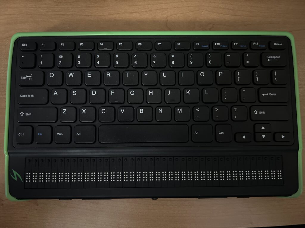 A photo of a Mantis Q40 braille display. The device is the size of a laptop keyboard with 40 routing keys below the keyboard and above 40 cells of 8 dot Braille. 