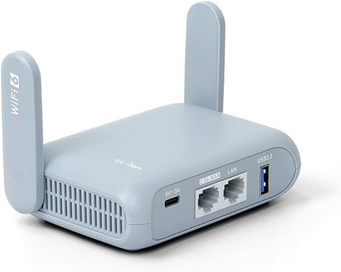 Light grey Beryl AX travel router with two upright antennas. The rear panel shows ports including a USB-C power input, a 2.5G WAN port, a LAN port, and a USB 3.0 port. The left antenna has ‘WiFi 6’ printed on it.